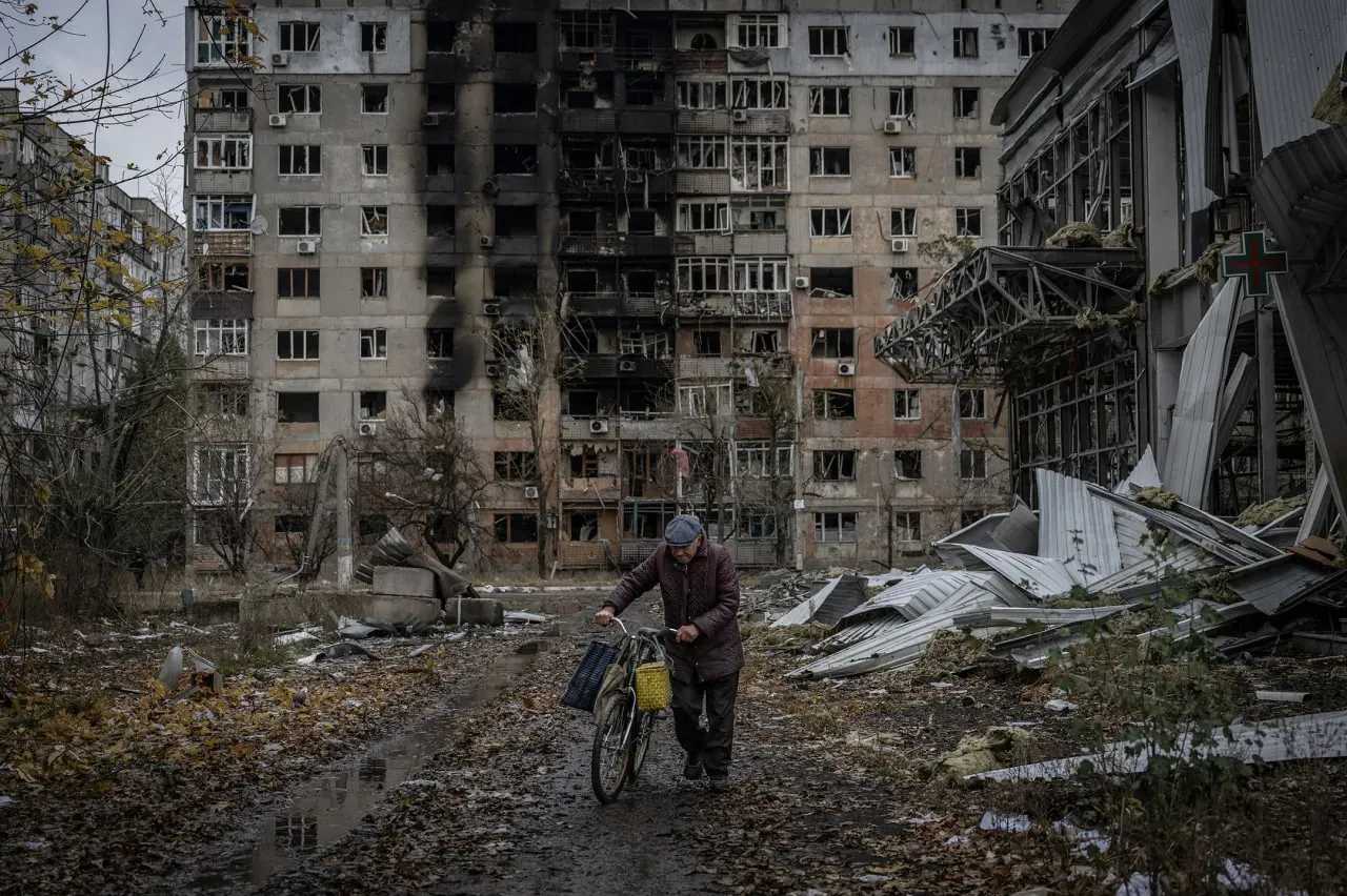 Civilian walks with bicycle through destroyed street in Avdiivka after Russian shelling