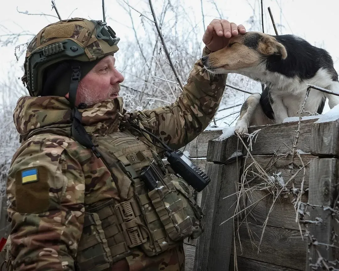 Ukrainian soldier in trench near Kharkiv frontline pets a dog during combat duty